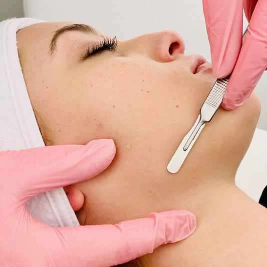 Esthetician demonstrating dermaplaning technique during professional Dermaplaning Training—removing peach fuzz for smooth skin."
